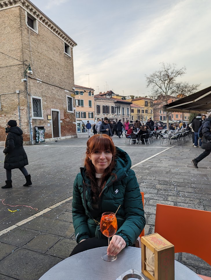 A photo of me sat drinking an Aperol spritz in a piazza in Venice.