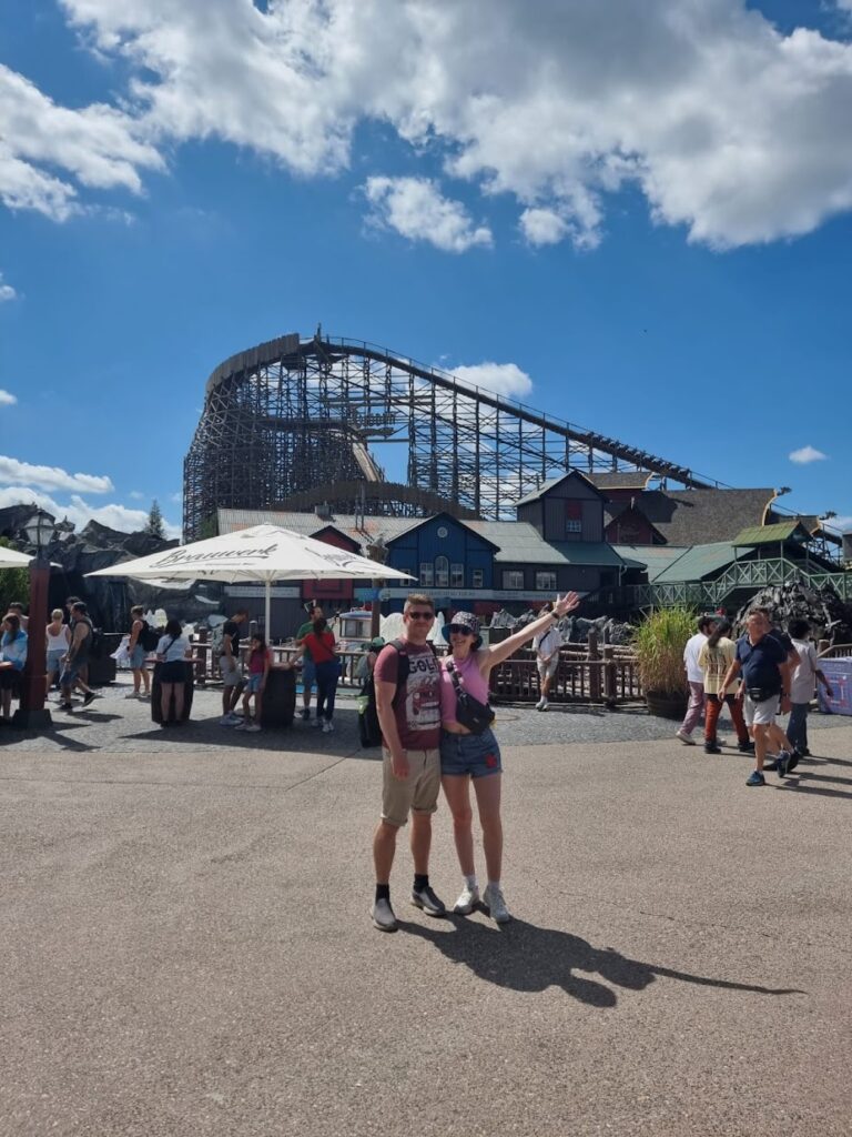 A couple stood in front of a rollercoaster